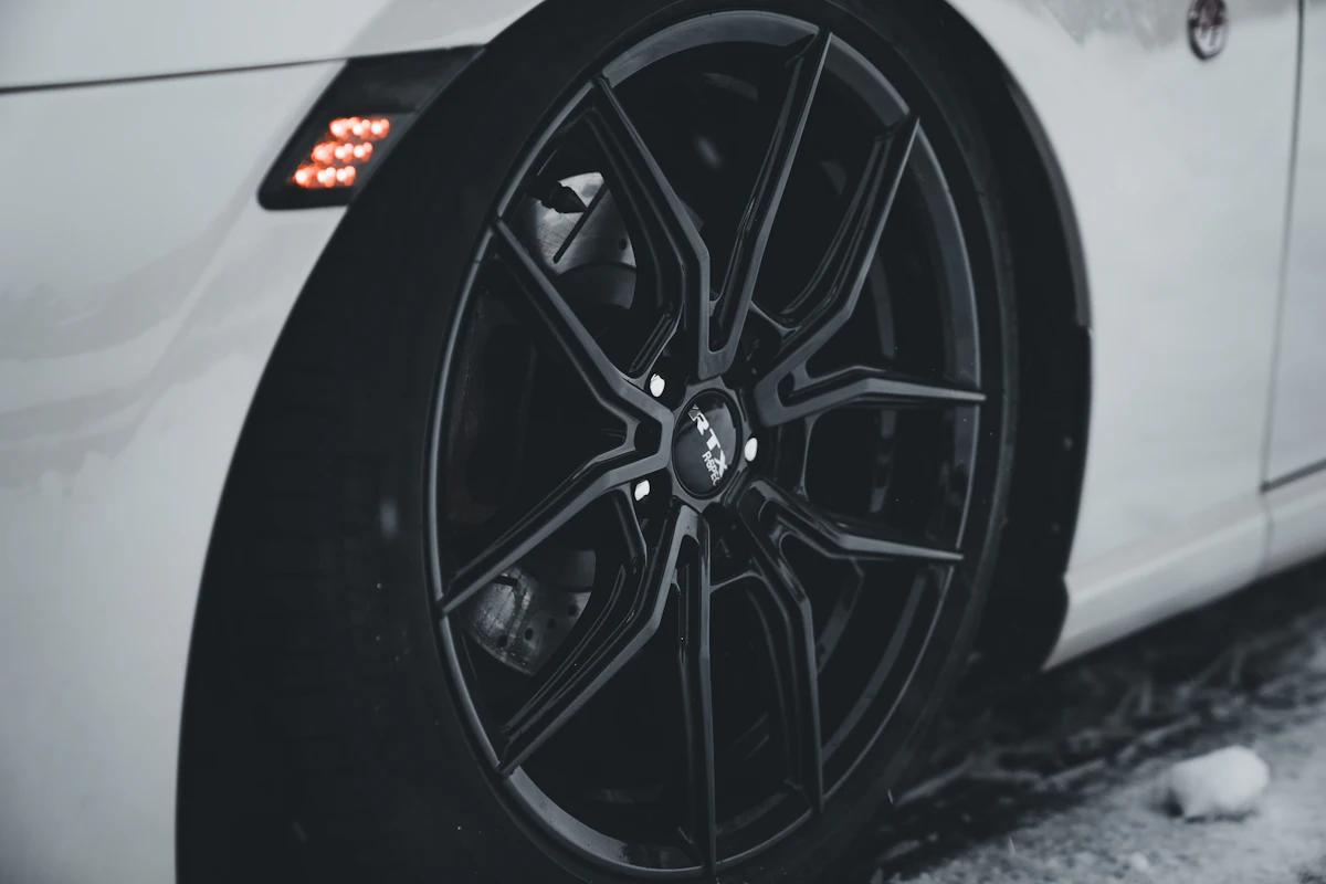 Close-up of a gloss black multi-spoke alloy wheel on a white car